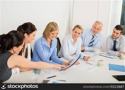Business Team sitting around meeting table discussing file