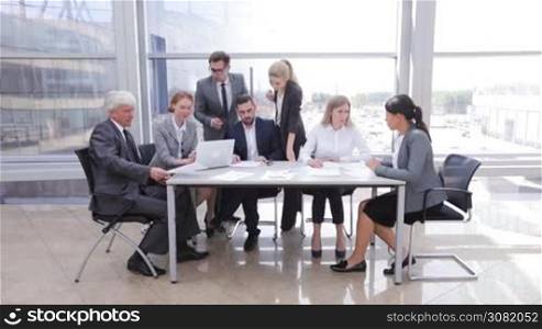 Business team sitting by the table with laptop and documents in office