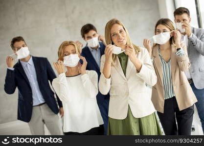 Business team taking off their protective facial mask and looking at the camera in the office