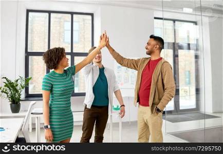 business, teamwork and corporate concept - happy creative team making high five at office. happy creative team making high five at office