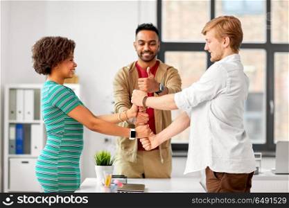business, teamwork and corporate concept - happy creative team making thumbs up gesture at office. happy creative team making high five at office. happy creative team making high five at office