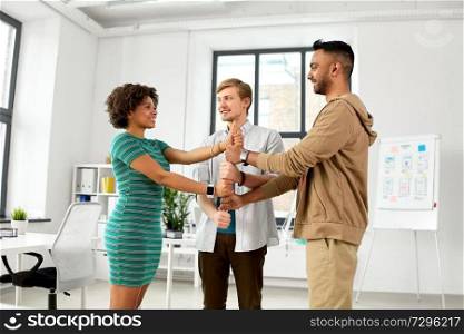 business, teamwork and corporate concept - happy creative team making thumbs up gesture at office. happy creative team making high five at office