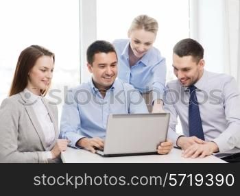 business, teamwork and office concept - smiling business team working with laptop computer in office