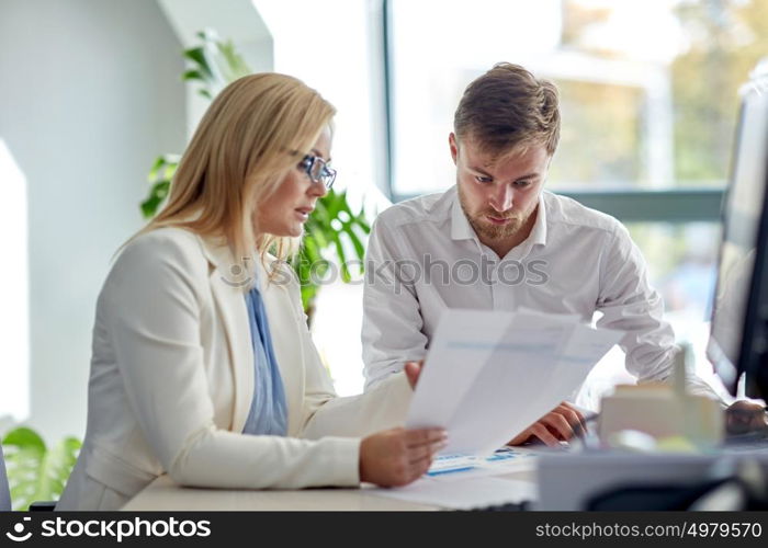 business, teamwork and people concept - creative team discussing papers at office table. business team discussing papers at office table