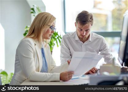 business, teamwork and people concept - creative team discussing papers at office table. business team discussing papers at office table