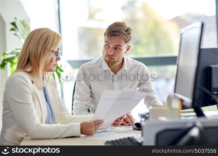 business, teamwork and people concept - creative team discussing papers at office table. business team discussing papers at office table