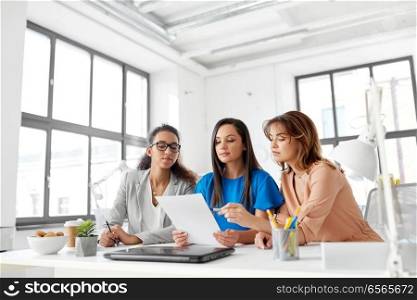 business, teamwork and people concept - female team or businesswomen discussing papers at office. businesswomen discussing papers at office