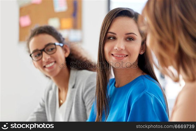 business, teamwork and people concept - female team or businesswomen talking at office. businesswomen talking at office. businesswomen talking at office