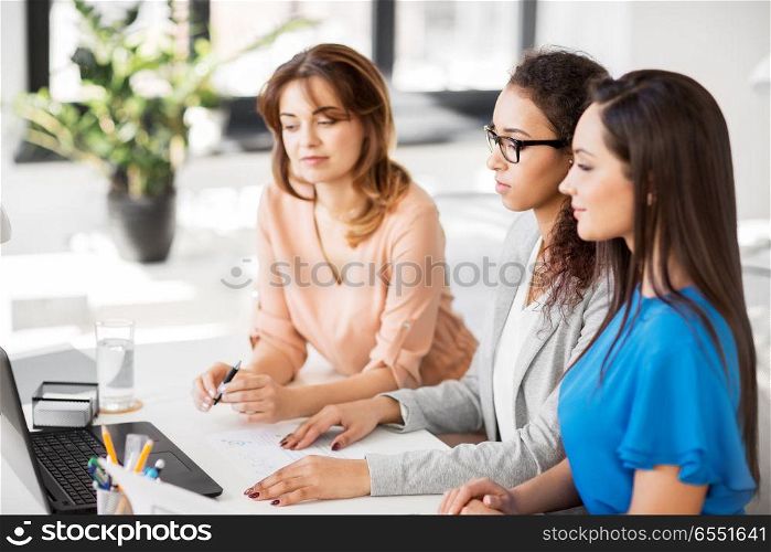 business, teamwork and people concept - female team or businesswomen with laptop computer working at office. businesswomen with laptop working at office. businesswomen with laptop working at office