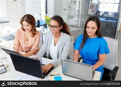 business, teamwork and people concept - female team or businesswomen with tablet pc and laptop computers working at office. businesswomen with tablet pc and laptops at office. businesswomen with tablet pc and laptops at office