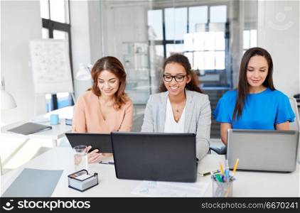 business, teamwork and people concept - female team or businesswomen with tablet pc and laptop computers working at office. businesswomen with tablet pc and laptops at office. businesswomen with tablet pc and laptops at office