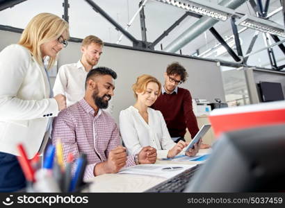 business, teamwork and people concept - international creative team with papers and tablet pc computers at office. business team with tablet pc and papers at office