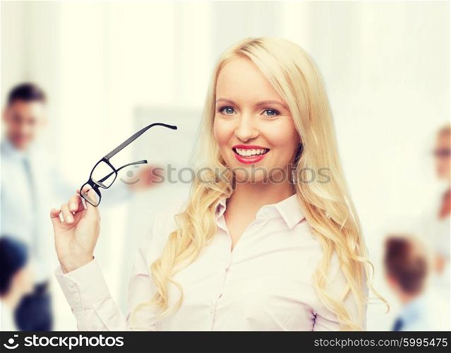business, teamwork and people concept - smiling businesswoman, student or secretary with eyeglasses over office and group of colleagues background