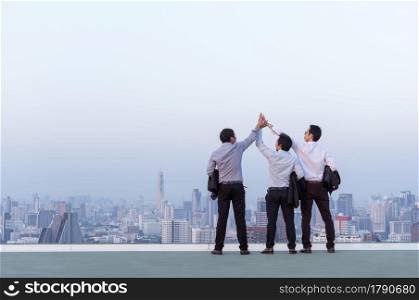 Business teamwork, businessman standing at the top of the building, holding hands showing success and looking through the scenery of the city.. business teamwork concept