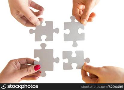 business, teamwork, cooperation, compatibility and connection concept - close up of hands connecting puzzle pieces