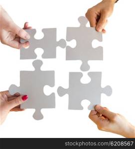 business, teamwork, cooperation, compatibility and connection concept - close up of hands connecting puzzle pieces