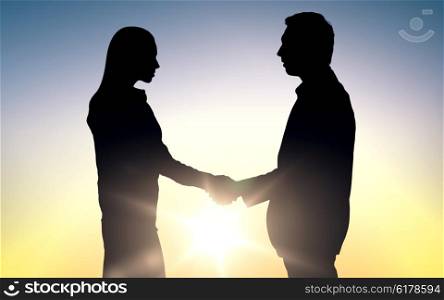business, teamwork, partnership, cooperation and people concept - business people shaking hands standing over sun light background