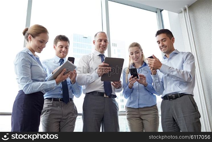 business, teamwork, people and technology concept - business team with tablet pc and smartphones meeting in office