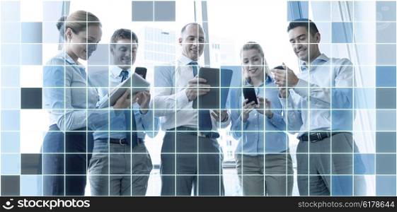 business, teamwork, people and technology concept - business team with tablet pc and smartphones meeting in office over blue squared grid background