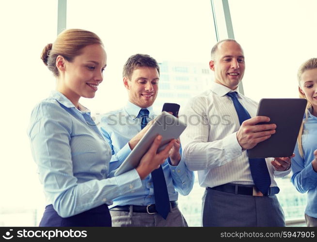 business, teamwork, people and technology concept - business team with tablet pc and smartphones in office