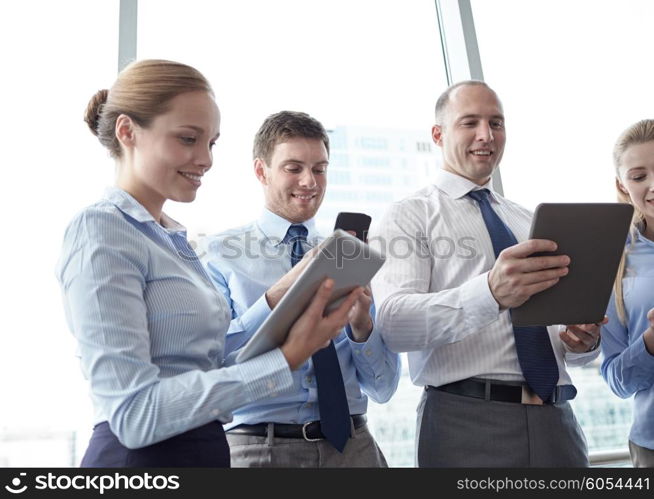 business, teamwork, people and technology concept - business team with tablet pc and smartphones in office