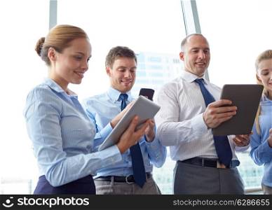 business, teamwork, people and technology concept - business team with tablet pc and smartphones in office