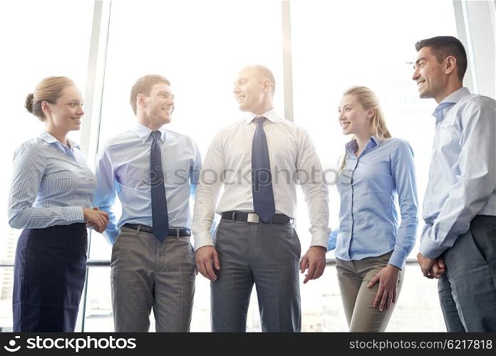 business, teamwork, people and technology concept - smiling business team meeting and talking in office