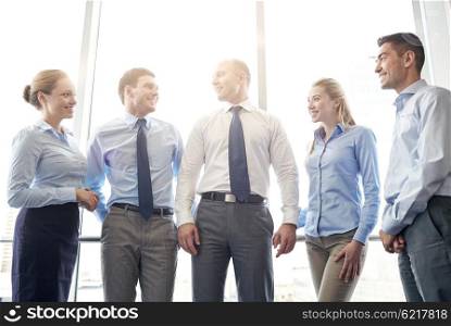 business, teamwork, people and technology concept - smiling business team meeting and talking in office