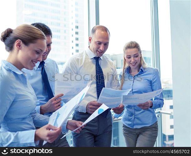 business, teamwork, people and technology concept - smiling business team with papers meeting in office