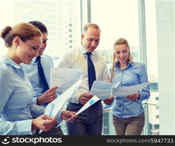 business, teamwork, people and technology concept - smiling business team with papers meeting in office