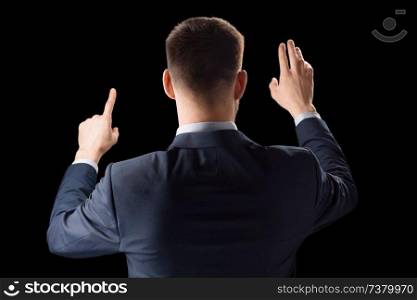 business, technology and augmented reality concept - businessman in suit working with invisible virtual screen over black background. businessman working with invisible virtual screen