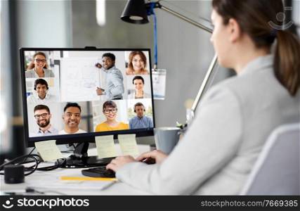 business, technology and communication concept - businesswoman with computer having video conference with colleagues at office. businesswoman having video conference on computer