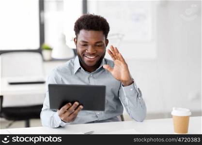 business, technology and communication concept - happy smiling african american businessman having video chat on tablet pc computer at office. businessman having video chat on tablet at office. businessman having video chat on tablet at office