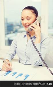 business, technology and communication concept - smiling businesswoman with phone, laptop and files in office