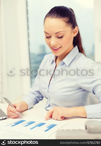 business, technology and communication concept - smiling businesswoman with phone, laptop and files in office