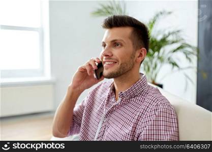 business, technology and communication concept - smiling young man calling on smartphone at office. smiling young man calling on smartphone at office