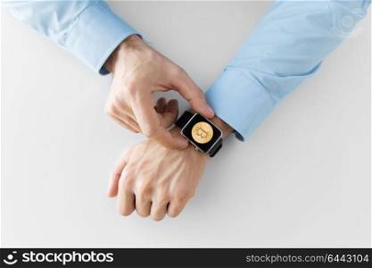 business, technology and cryptocurrency concept - close up of male hand wearing smart watch with bitcoin on screen. close up of hands with bitcoin on smart watch