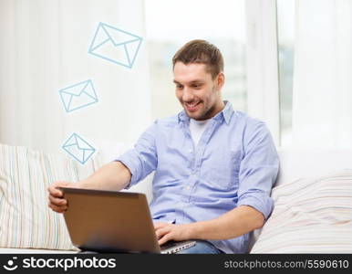 business, technology and e-learning concept - smiling man working with laptop at home