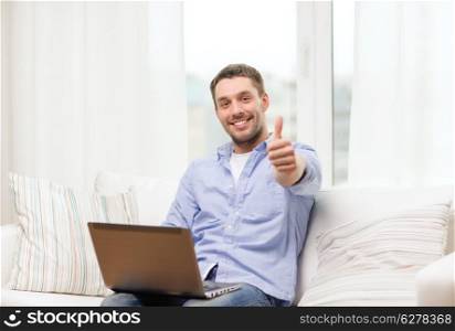 business, technology and e-learning concept - smiling man working with laptop at home