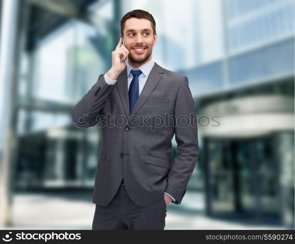 business, technology and education concept - friendly young smiling businessman with smartphone