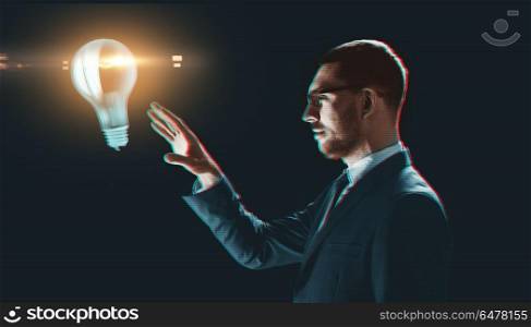 business, technology and efficiency concept - businessman in suit with virtual projection of light bulb over black background. businessman with virtual light bulb projection. businessman with virtual light bulb projection