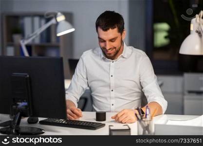 business, technology and internet of things concept - happy businessman using smart speaker at night office. businessman using smart speaker at night office