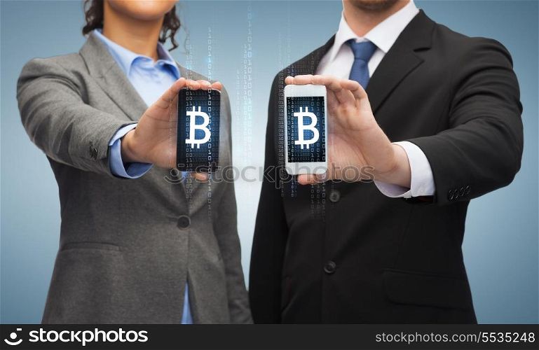 business, technology and internetconcept - businessman and businesswoman with bitcoin sign on smartphone screens