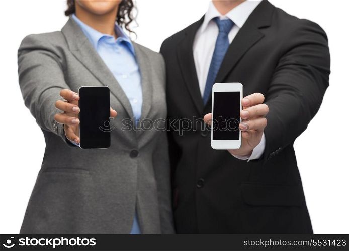 business, technology and internetconcept - businessman and businesswoman with blank black smartphone screens