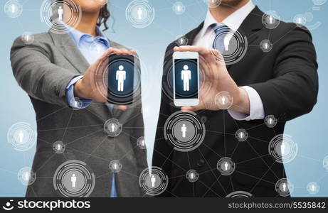 business, technology and internetconcept - businessman and businesswoman with social or business network on smartphone screens