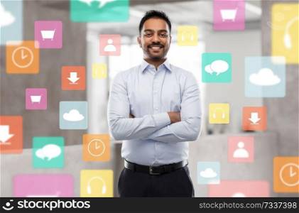 business, technology and multimedia concept - smiling indian businessman with app icons over office background. indian businessman with app icons at office