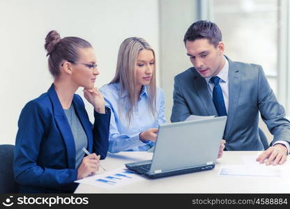 business, technology and office concept - concentrated business team with laptop computers and documents having discussion in office