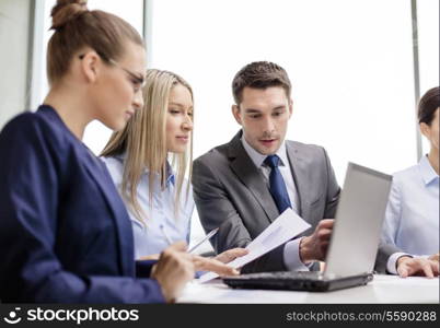 business, technology and office concept - concentrated business team with laptop computers and documents having discussion in office