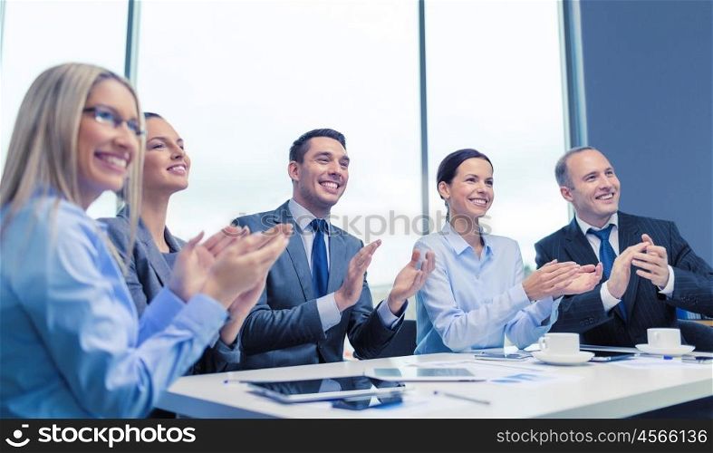 business, technology and office concept - happy business team with laptop computers, documents and coffee clapping hand