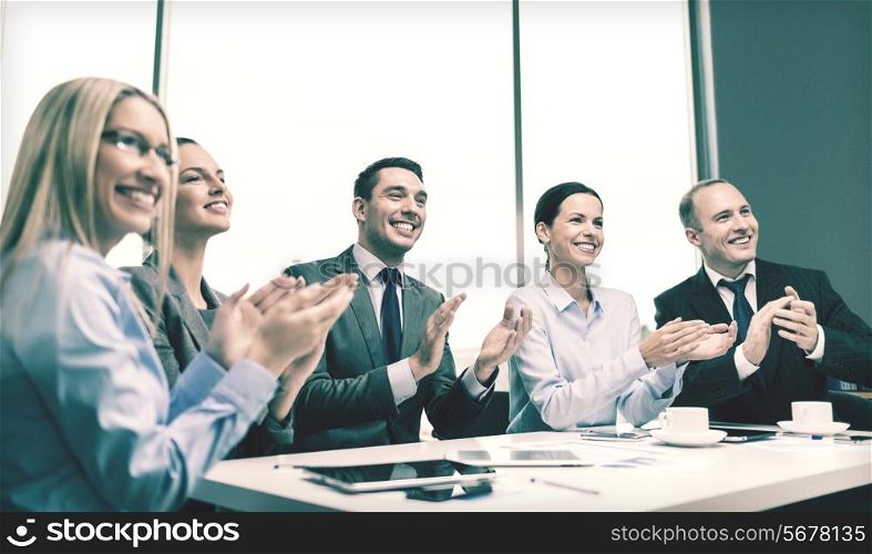 business, technology and office concept - happy business team with laptop computers, documents and coffee clapping hand